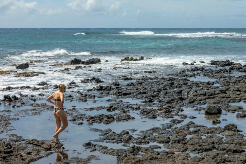 Woman walking along rocky coastline of Kauai